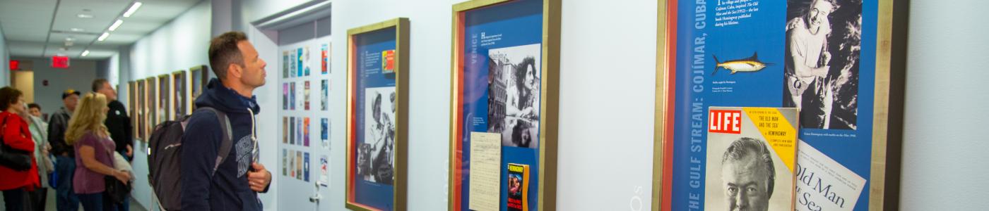 Museum visitors examine the Hemingway: A Life Inspired exhibit gallery.