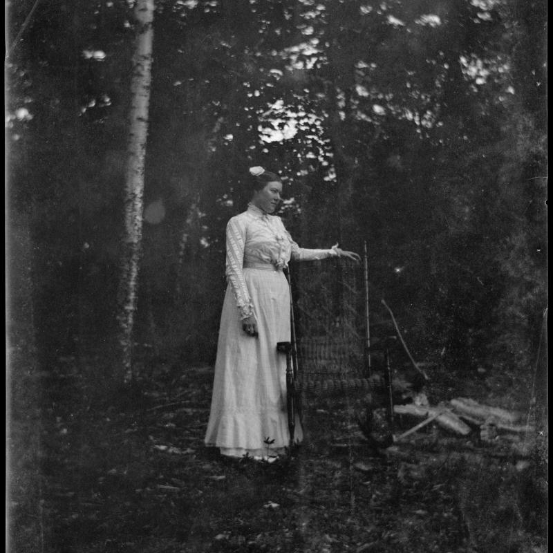 Grace Hall Hemingway in a white dress poses, standing, in a clearing near Walloon Lake, Michigan, c. 1900