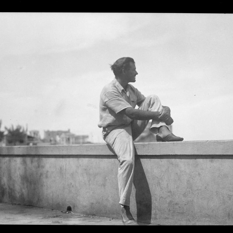 Hemingway, seated on the sea wall at Cojimar, Cuba, looking into the distance.  Early 1930s