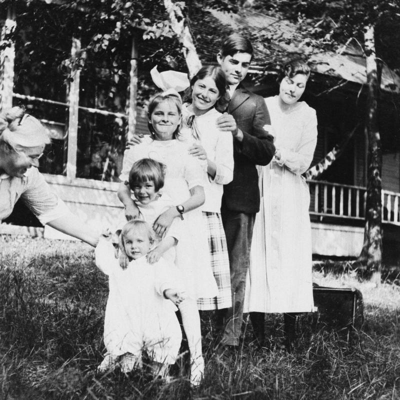 The Hemingway siblings lined up in order of age in front of the family's cottage, Windemere, on Walloon Lake, Michigan, 1916.  Their mother, Grace Hall Hemingway, helps steady the baby, Leicester, standing in front of his older siblings.