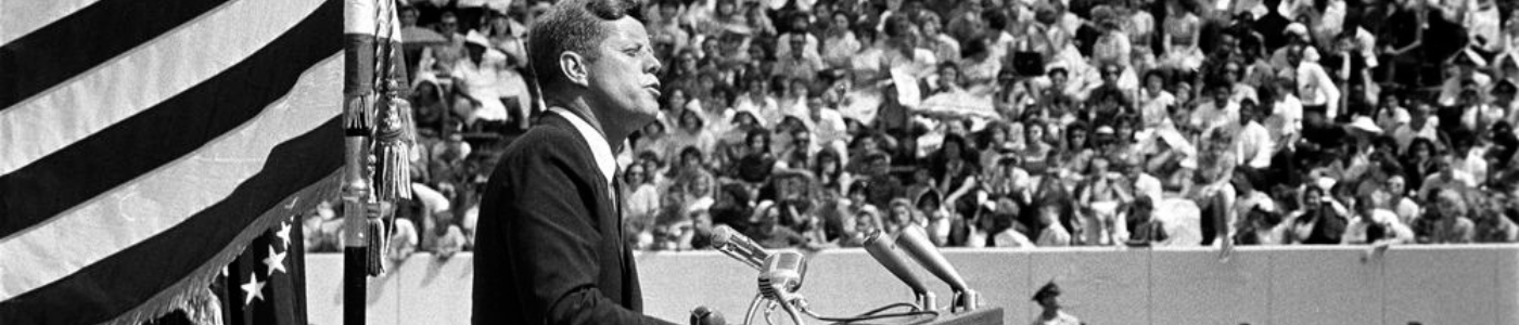 JFK, seen in profile, speaks from a podium in Rice University Stadium