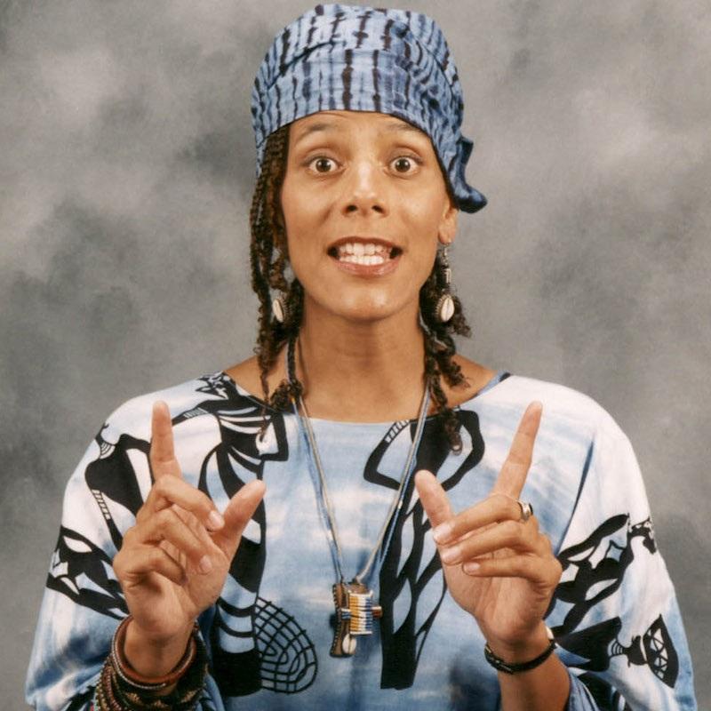 Image of Valerie Tutson, a storyteller, wearing a blue white and black shirt with matching head wrap.