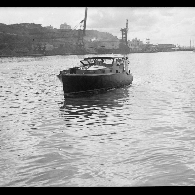 Hemingway's fishing boat, the Pilar, underway in Havana harbor, with Hemingway at the helm.